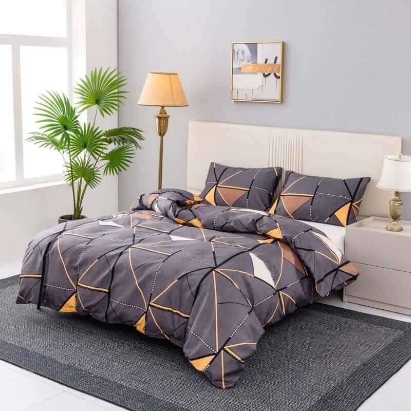 Geometric patterned bedspread on a bed in a well-lit bedroom with decor elements.