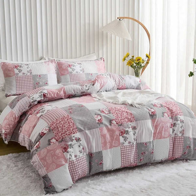 Patchwork quilt set with pink and gray patterns on a bed in a bright room.