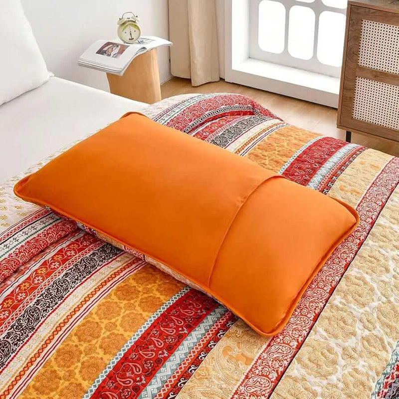 Bed with patterned quilt and pillows in a bedroom setting