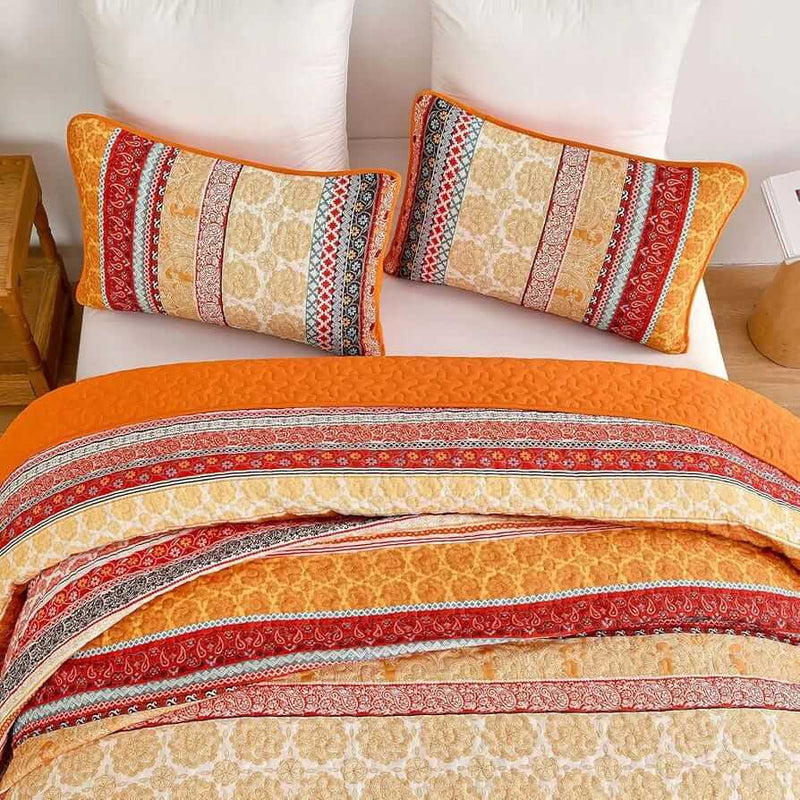 Bed with patterned quilt and pillows in a bedroom setting