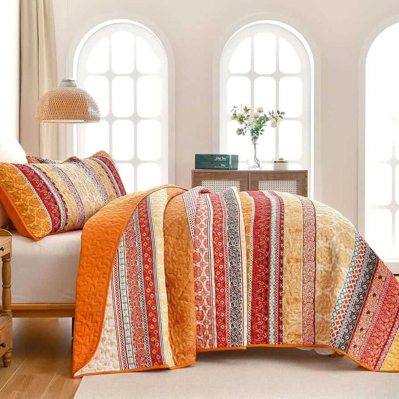 Bed with patterned quilt and pillows in a bedroom setting