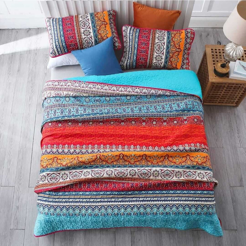 Colorful patterned bedding set on a bed with pillows in a bedroom setting.