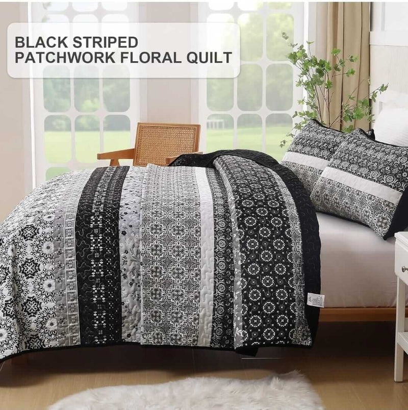 A colorful floral patterned cotton bedspread set on a bed, with a variety of matching and contrasting pillows, in a room with wooden furniture and a lamp.