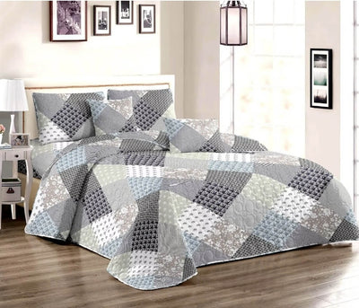 Gray and white patchwork quilt on a bed in a bedroom setting.