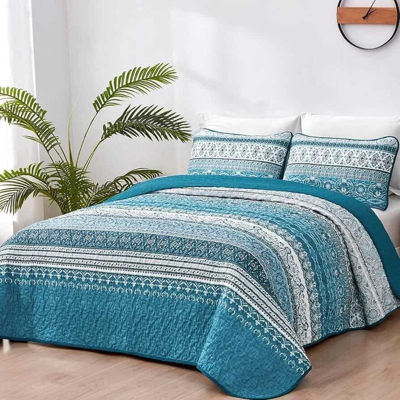 Bed with patterned quilt and pillows in a bedroom setting