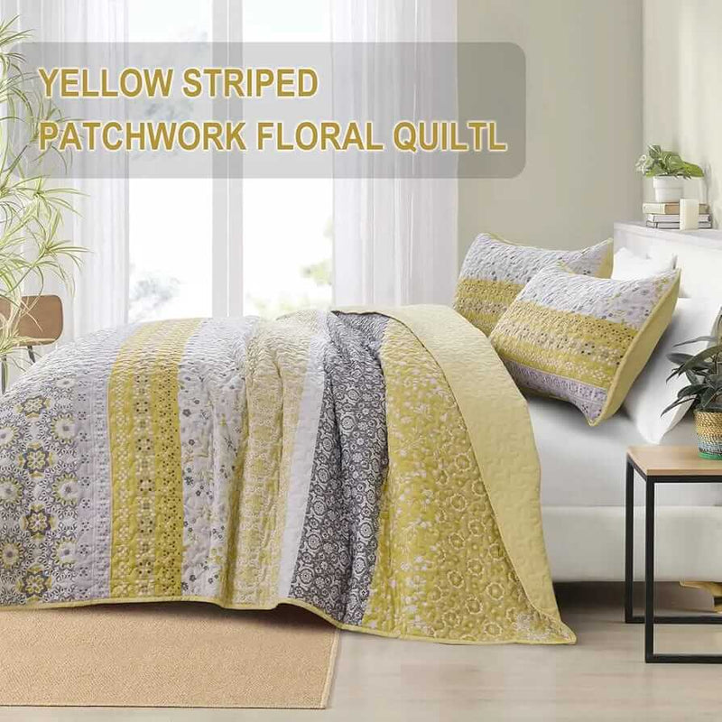 A colorful floral patterned cotton bedspread set on a bed, with a variety of matching and contrasting pillows, in a room with wooden furniture and a lamp.