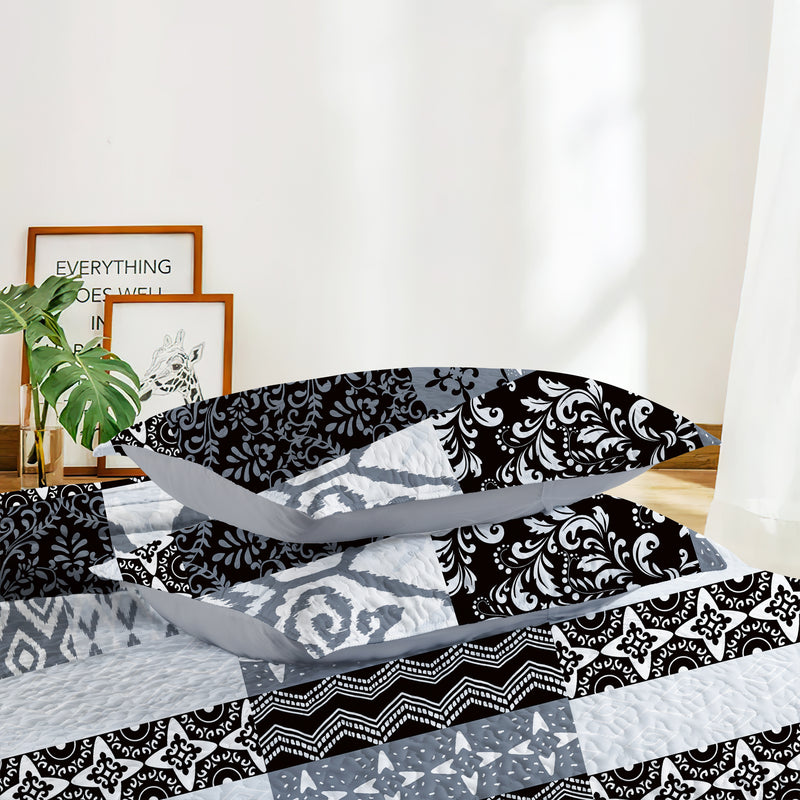 Black and white patterned bedding set on a bed with a neutral background