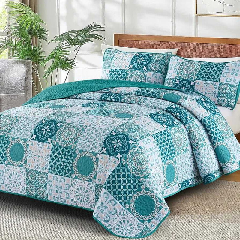 A colorful floral patterned cotton bedspread set on a bed, with a variety of matching and contrasting pillows, in a room with wooden furniture and a lamp.