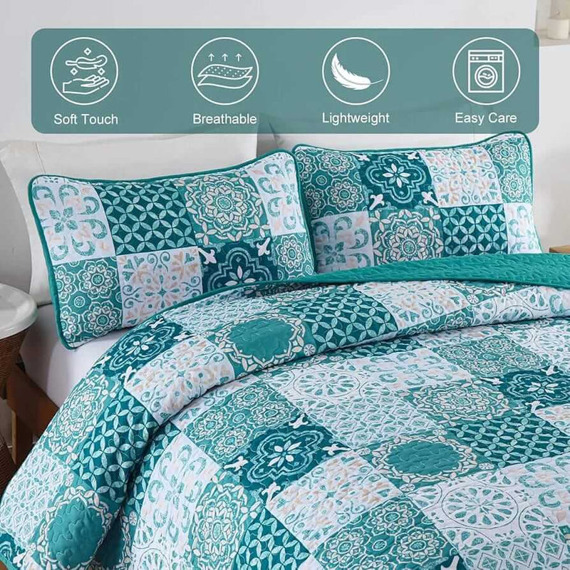 A colorful floral patterned cotton bedspread set on a bed, with a variety of matching and contrasting pillows, in a room with wooden furniture and a lamp.