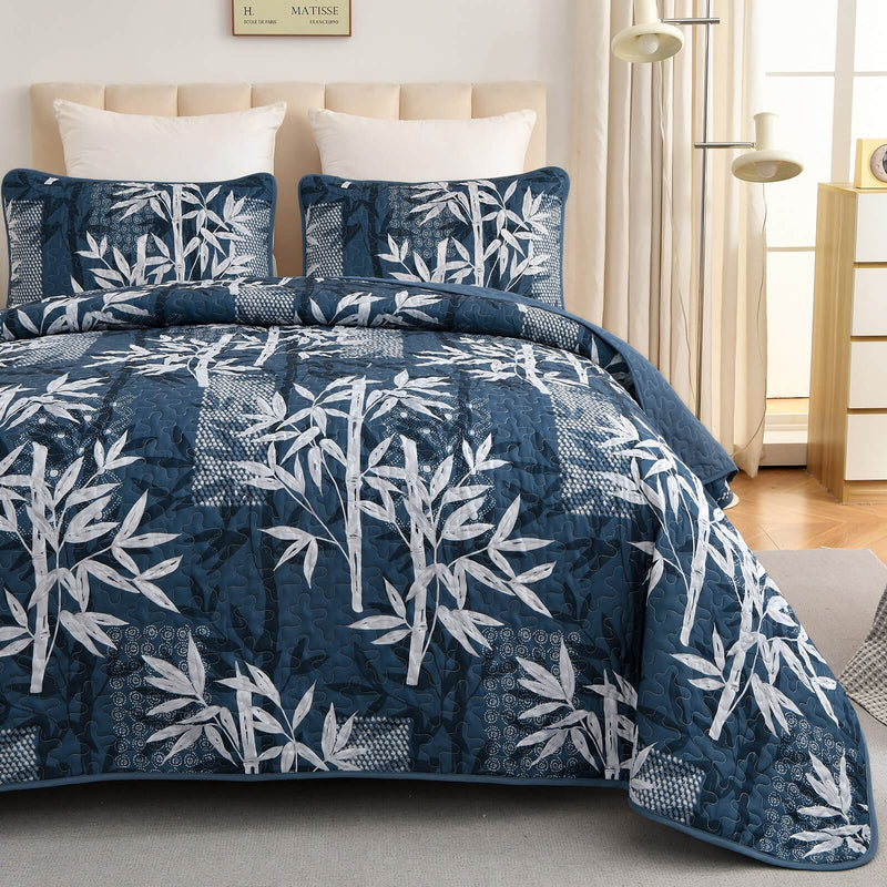 Blue and white leaf-patterned comforter set on a bed in a bedroom.