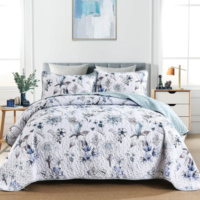 Floral patterned quilt set on a bed in a bedroom setting with a painting on the wall.
