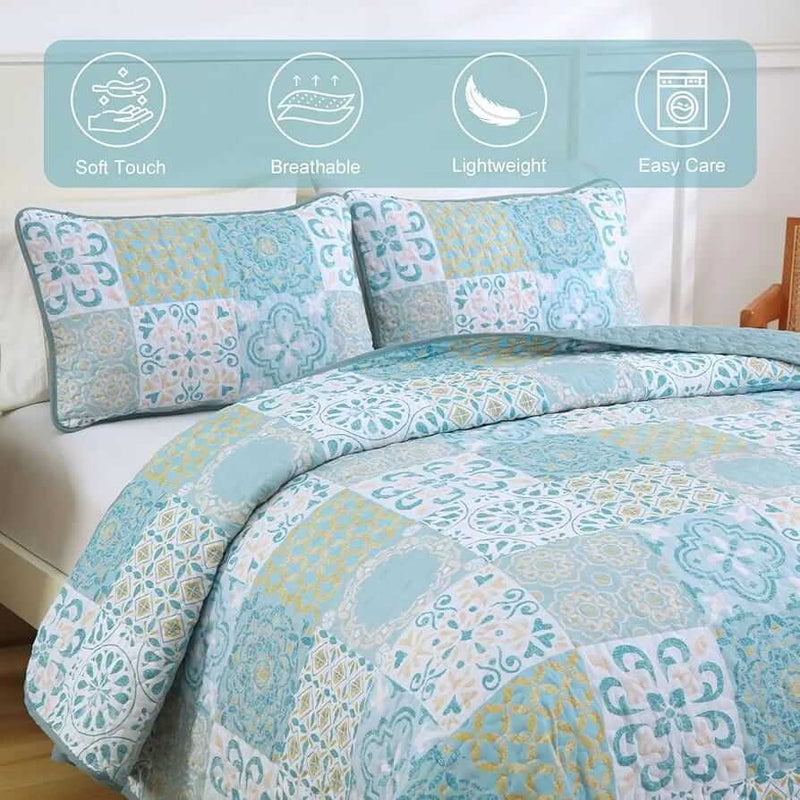Blue and green patchwork quilt set on a bed in a bedroom.
