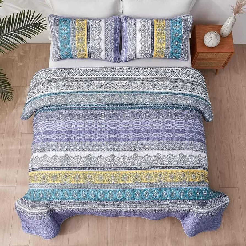 Bed with a colorful quilt and pillows in a bedroom setting.