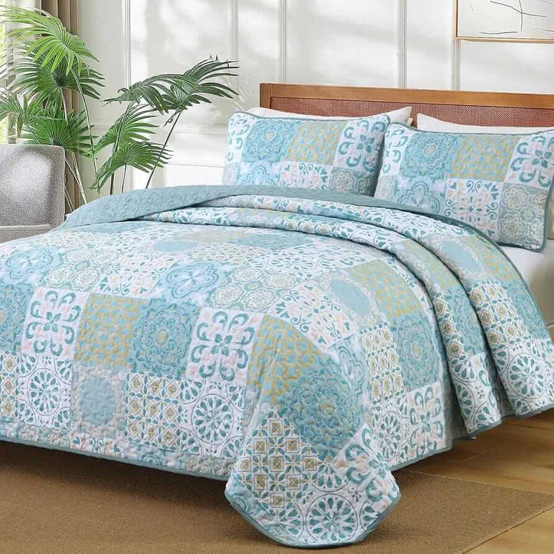 Blue and green patchwork quilt set on a bed in a bedroom.