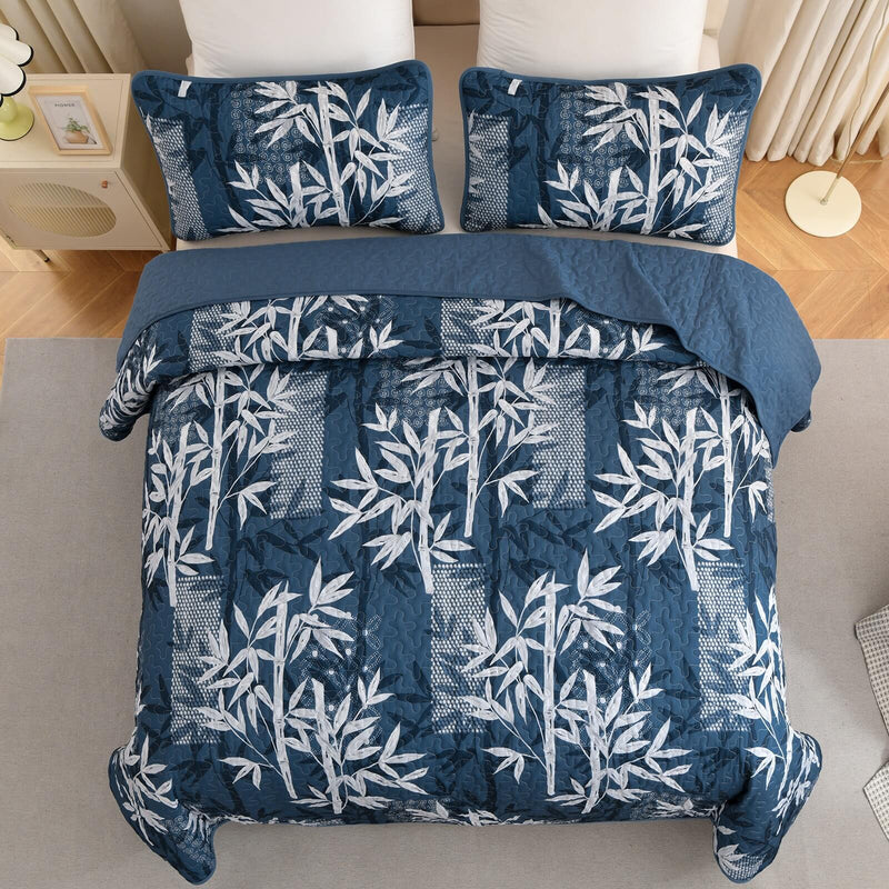 Blue and white leaf-patterned comforter set on a bed in a bedroom.
