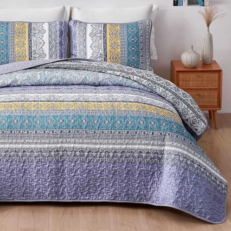 Bed with a colorful quilt and pillows in a bedroom setting.