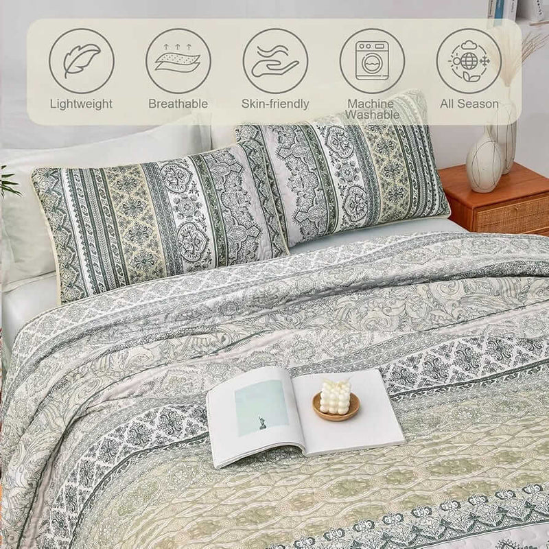 Patterned quilt set on a bed in a bedroom with a nightstand and plant.
