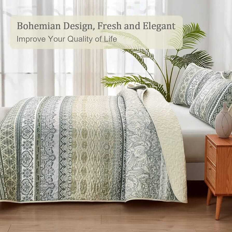Patterned quilt set on a bed in a bedroom with a nightstand and plant.