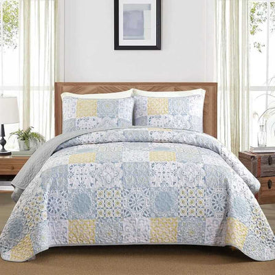 Patchwork quilt set on a bed in a bedroom with a wooden headboard.
