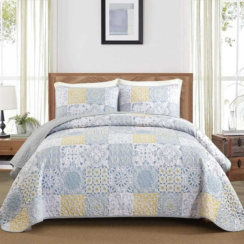 Patchwork quilt set on a bed in a bedroom with a wooden headboard.