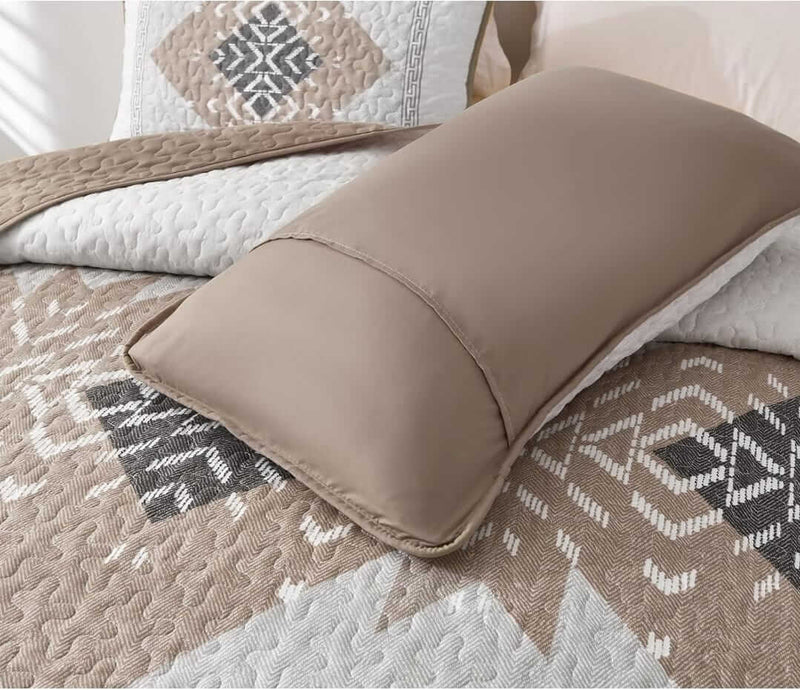 Bed with patterned quilt and pillows in a bedroom setting