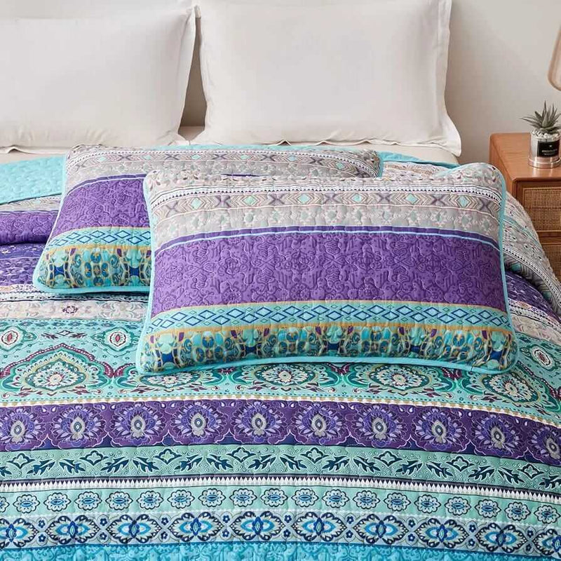 Bed with a colorful quilt and pillows in a bedroom setting.
