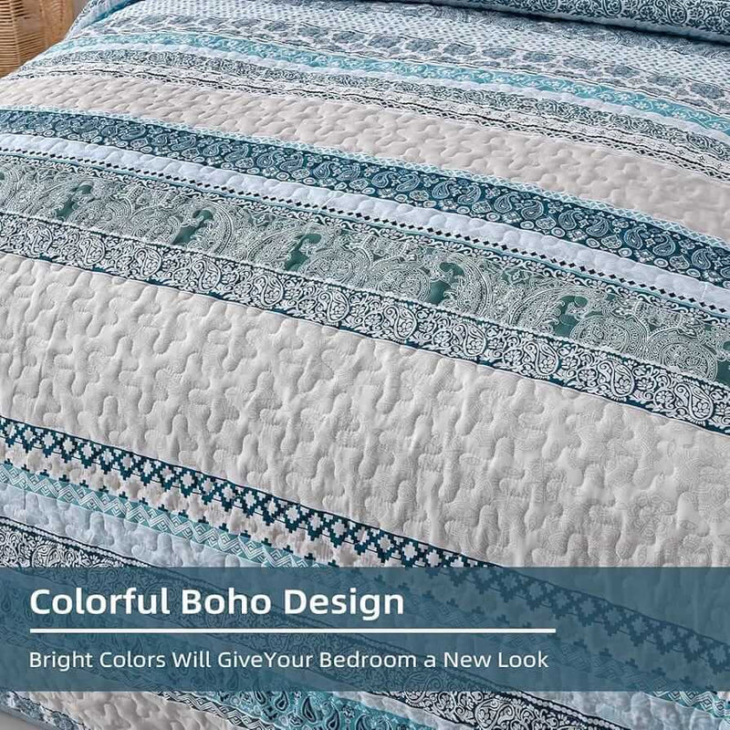 Patterned quilt set on a bed in a bedroom with a nightstand and plant.