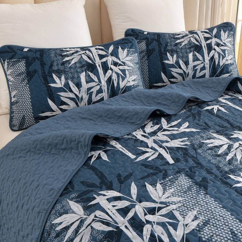 Blue and white leaf-patterned comforter set on a bed in a bedroom.