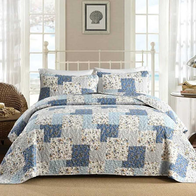 Quilt set with blue and beige geometric pattern on a bed in a bedroom.