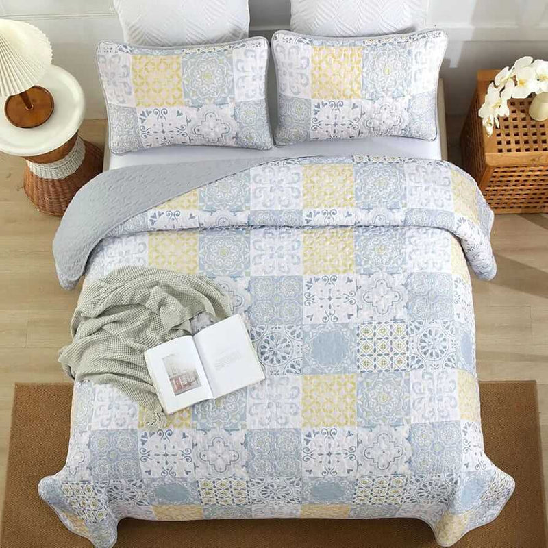 Patchwork quilt set on a bed in a bedroom with a wooden headboard.