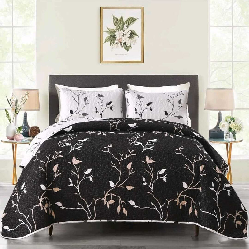 Bed with black floral-patterned comforter and matching pillows in a bedroom setting.
