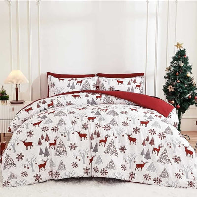 Christmas-themed bedding set with reindeer and trees on a bed in a room with a Christmas tree.