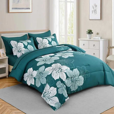 Teal floral bedding set on a bed in a bedroom with light-colored walls and wooden flooring.
