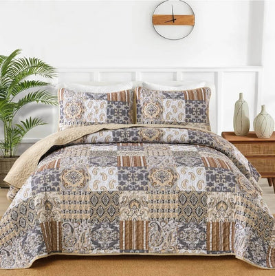 A colorful floral patterned cotton bedspread set on a bed, with a variety of matching and contrasting pillows, in a room with wooden furniture and a lamp.