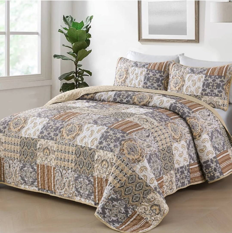 A colorful floral patterned cotton bedspread set on a bed, with a variety of matching and contrasting pillows, in a room with wooden furniture and a lamp.