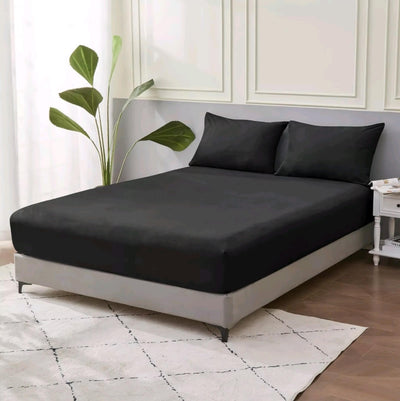 Black bed sheet set on a bed in a bedroom with a plant and nightstand.