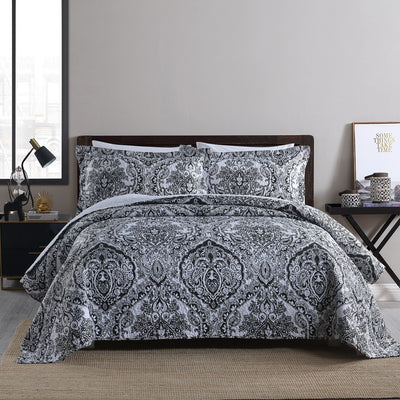 Bed with black and white patterned bedding in a bedroom setting.