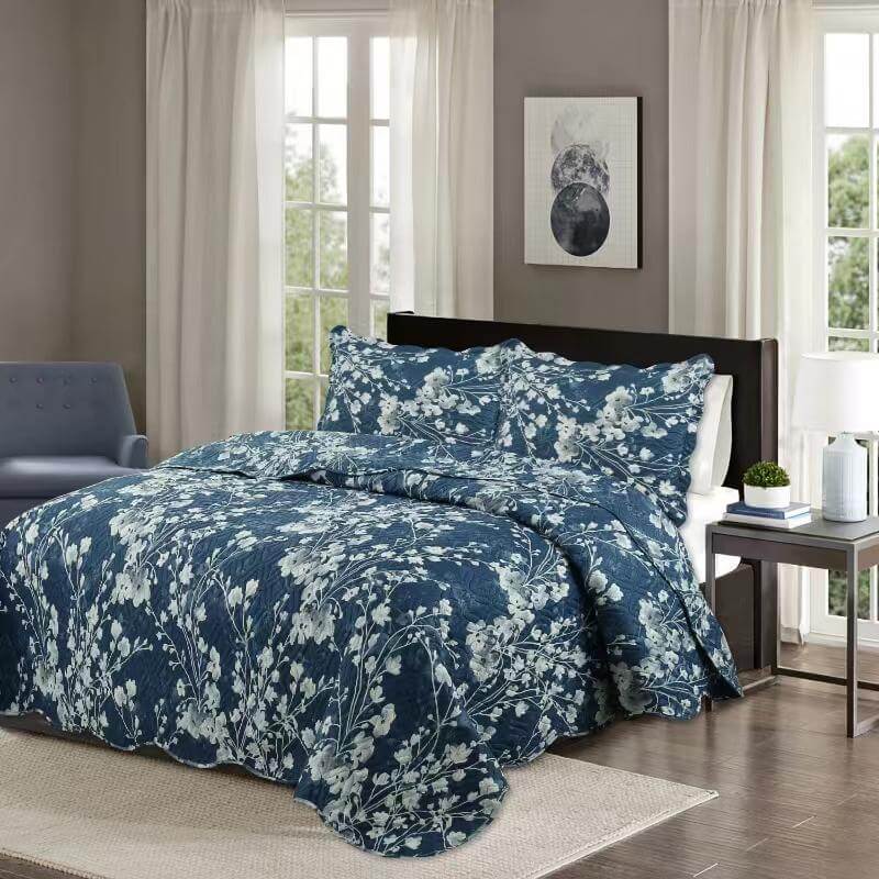 Blue floral bedding set in a bedroom with a gray chair and window.