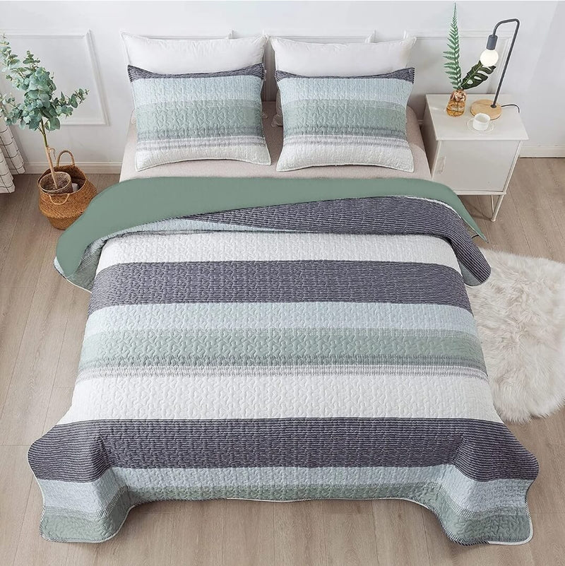 Striped quilt set on a bed in a bedroom with a nightstand and decor items.