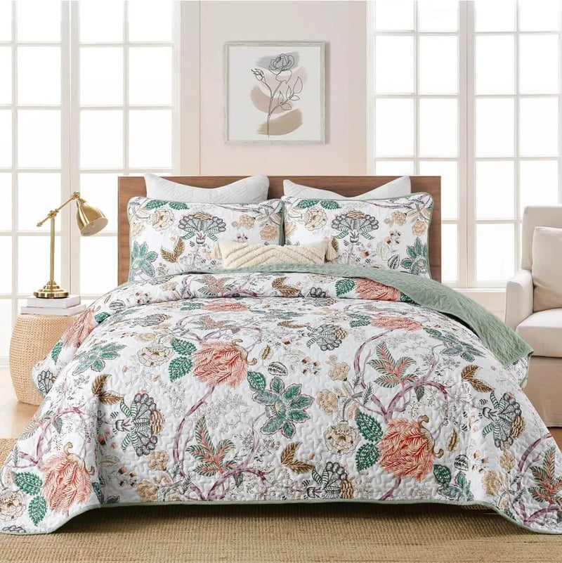 Floral bedding set on a bed in a bedroom with a lamp and artwork on the wall.