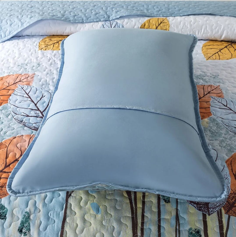 Blue pillow on a colorful quilt with leaf patterns
