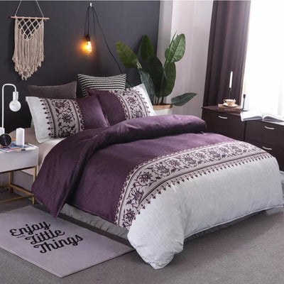 Purple and white patterned bedding set on a bed in a bedroom with decorative elements.