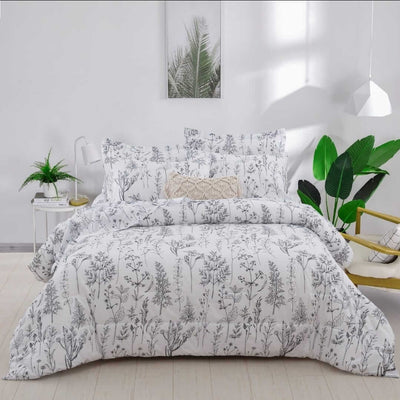 Floral patterned comforter set on a bed in a bright bedroom with plants.