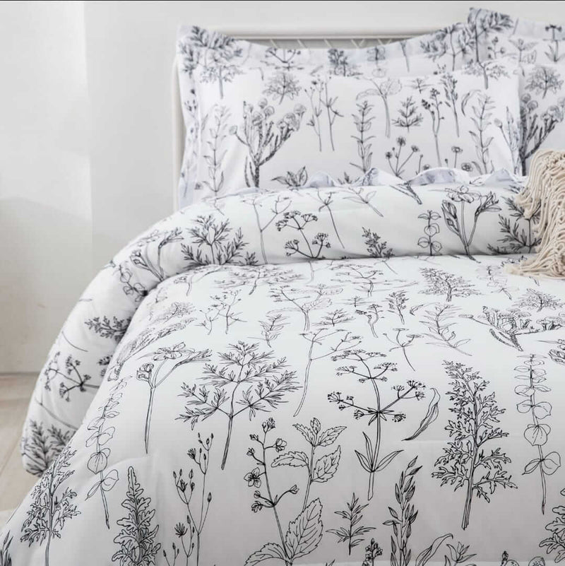 Bed with floral patterned bedding and pillows against a white wall.