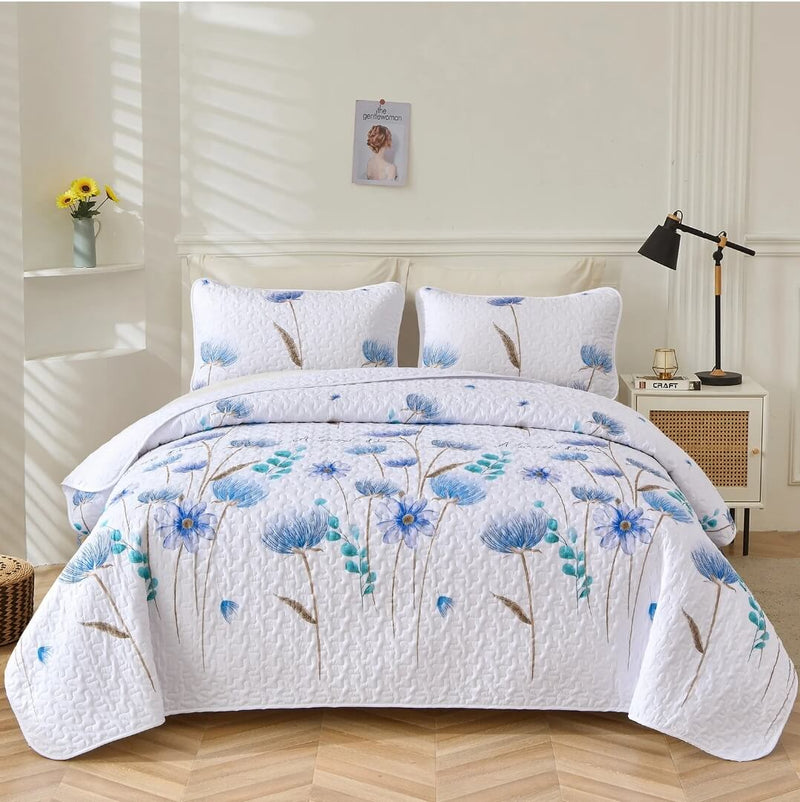 Floral quilt set on a bed in a bedroom with a lamp and decor items.